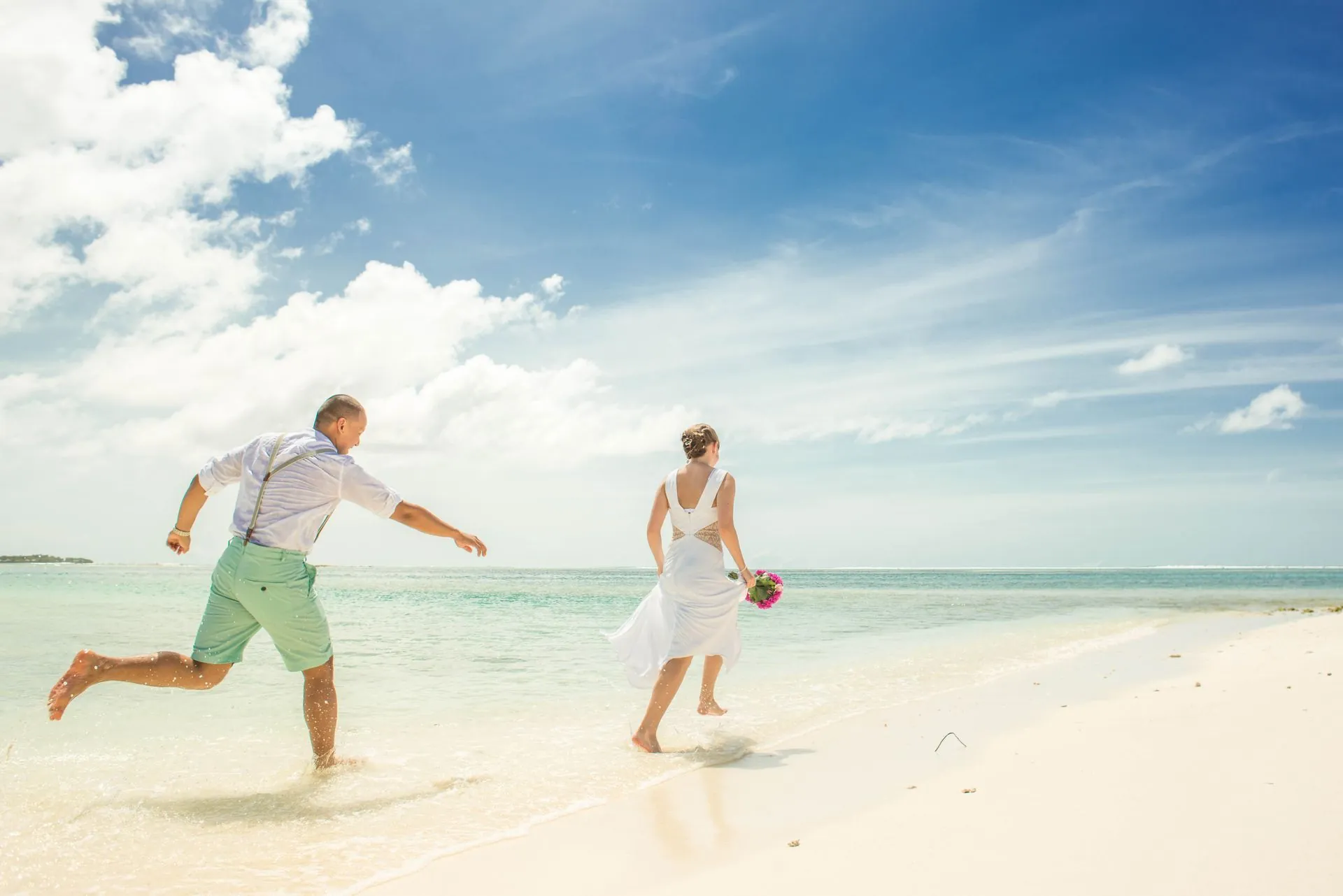 Pareja de recién casados corriendo felices por una playa de Costa Rica