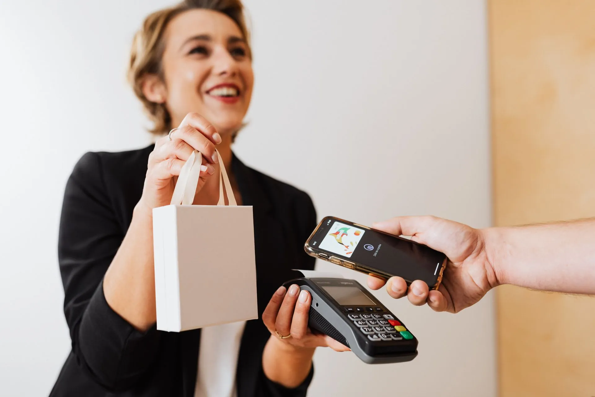 Smiling shop owner while a customer pays by tapping their phone