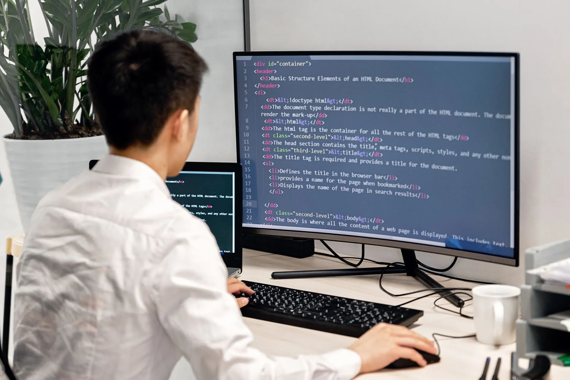 Web developer building a website on his computer in a bright office