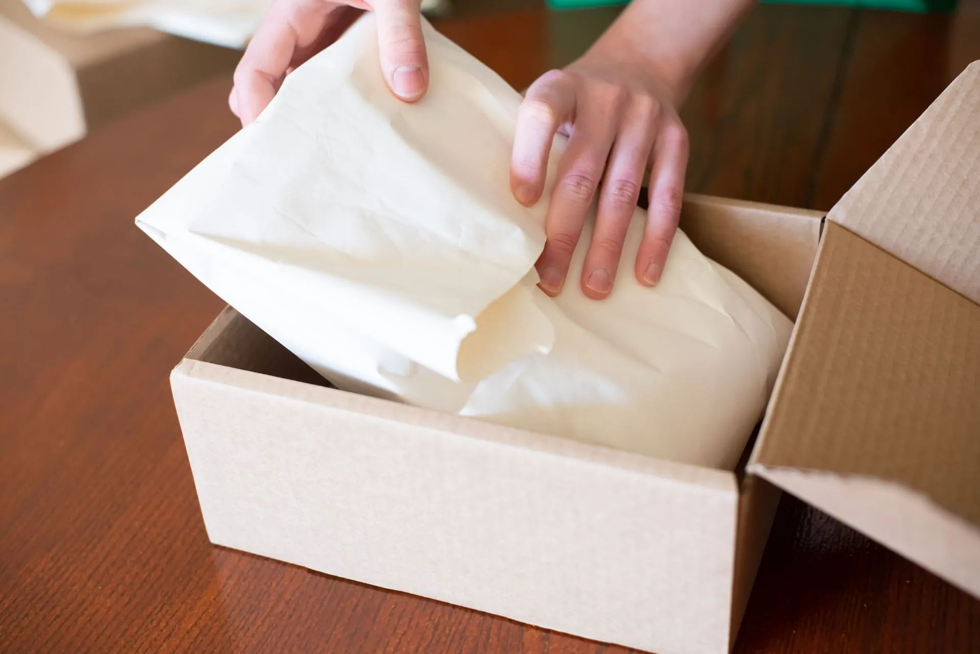 Person packing an online store order into a cardboard box